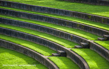 Sunlight leads the eye down the steps of the outdoor grass seating in the Rose Gardens Amphitheater, at Washington Park in Portland, Oregon